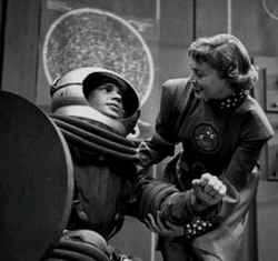 Actors Frankie Thomas and Margaret Garland in a scene from Tom Corbett, Space Cadet, showing Dr. Joan Dale assisting an astronaut in a bulky space suit.