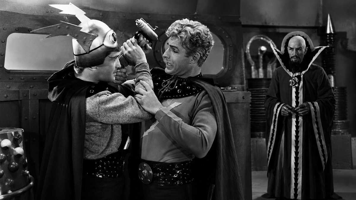 Composite scene as Flash Gordon struggles with Killer Kane aboard a retro spaceship while Emperor Ming the Merciless watches in the background from the 1936 Flash Gordon serial.