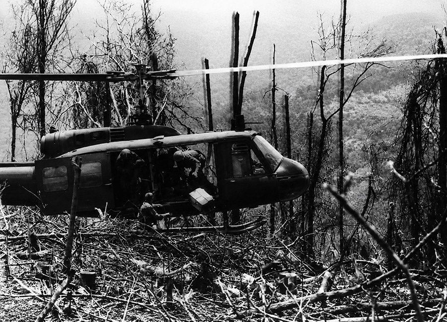 Bell UH-1 Huey helicopter hovering over a rough clearing west of Kontum in South Vietnam during 1968 operations near the Cambodian border.