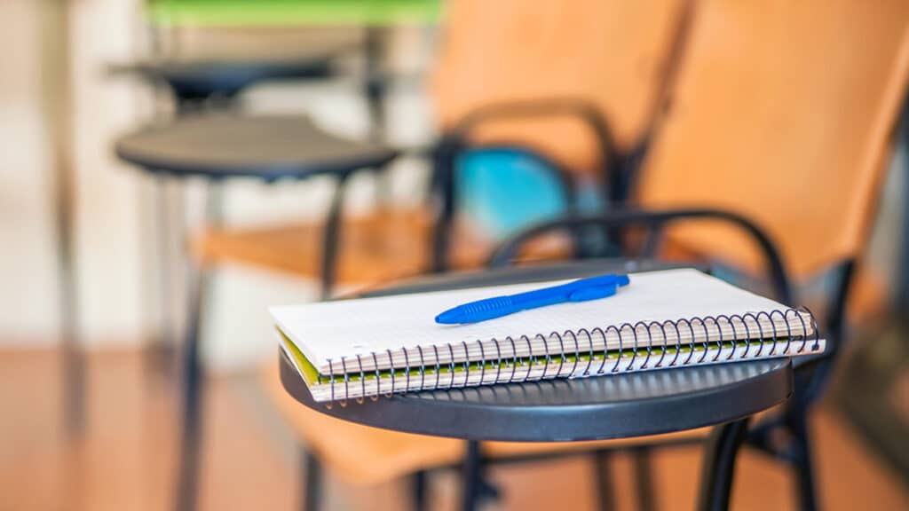 Pads and pen on classroom desk