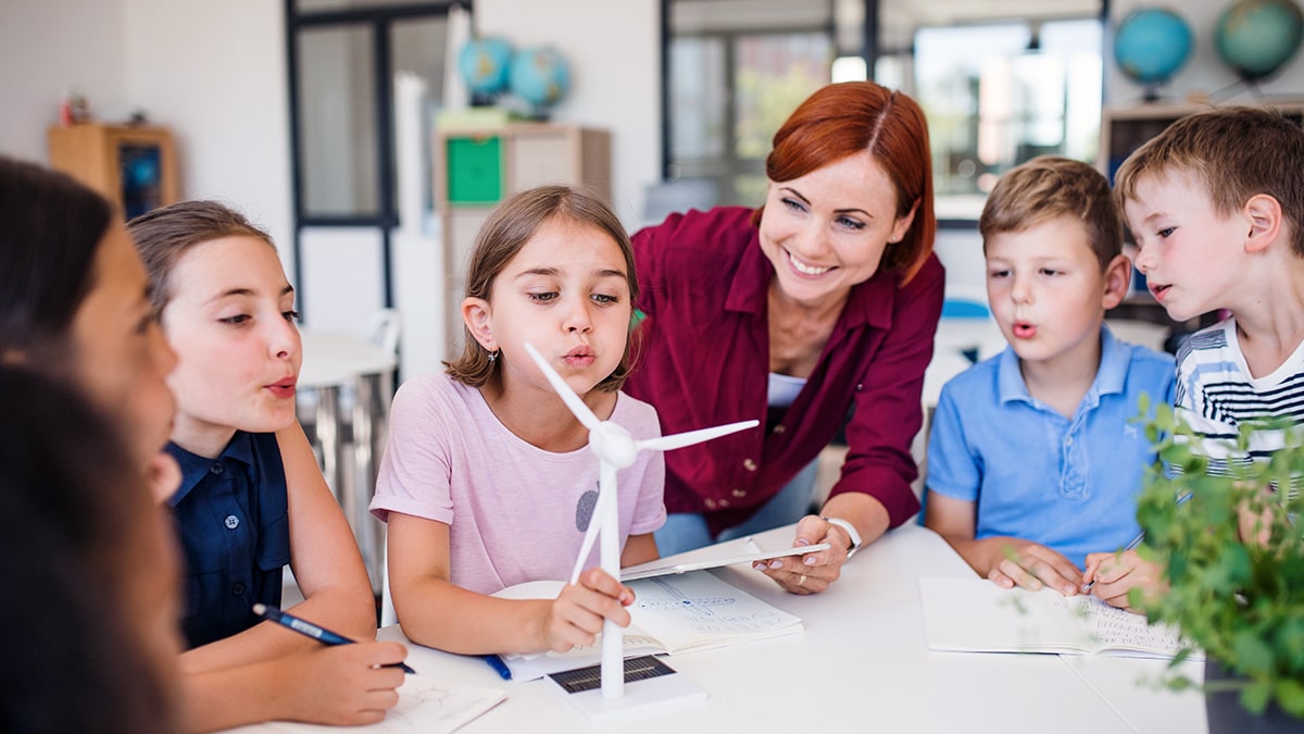 Teacher showing pupils a scale model wind turbine