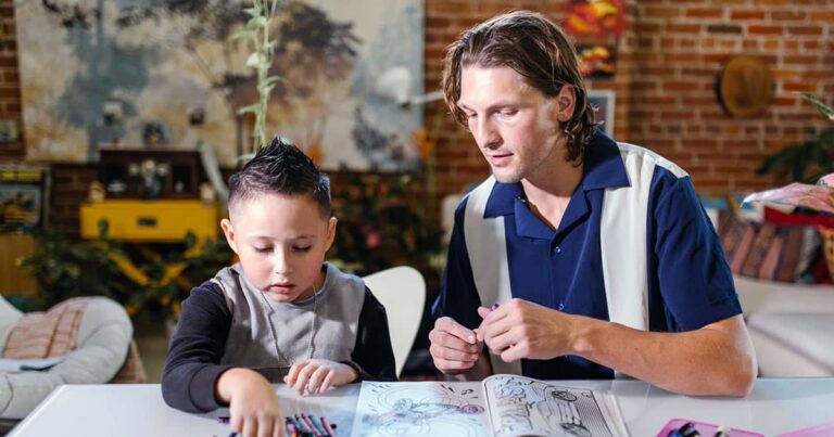 Man helping boy with crayon colouring in