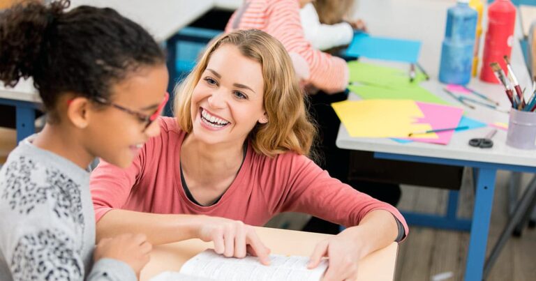 Teacher pointing to text on student's desk