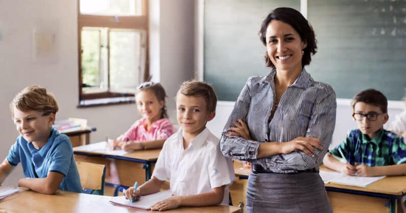 Teacher standing confidently in elementary classroom